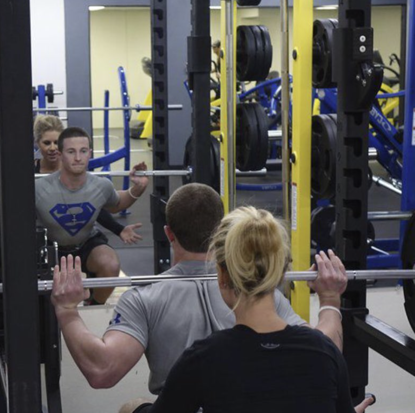 Trainer spotting a squat